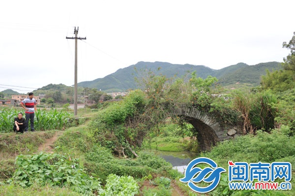 已廢棄的石拱橋，被野草覆蓋，下有溪流，村民稱此路