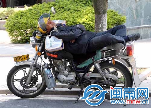 一載客的摩的師傅躺在摩托車上睡著了