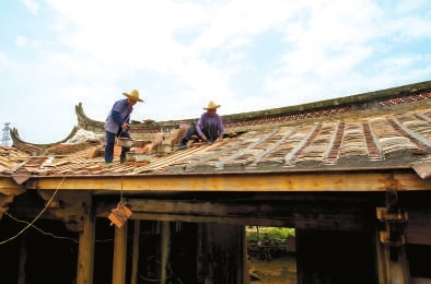 工人在鋪設孝友第屋頂上的瓦片。