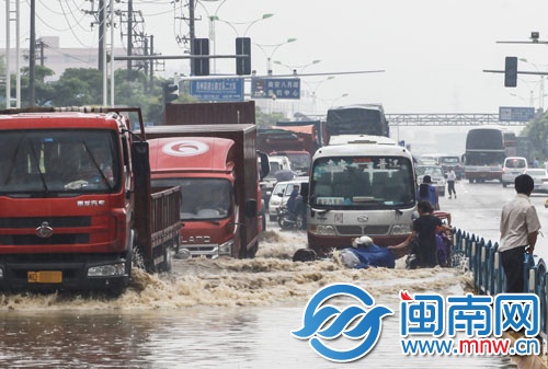 南環(huán)路上積水太深，摩托車在路中拋錨，市民躲上隔離欄
