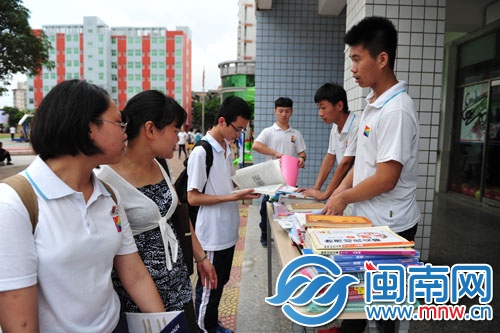 初一初二的學弟學妹在畢業(yè)送書攤點前挑選自己想要的