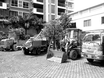 多輛工程車停放在小區(qū)公共綠化帶。