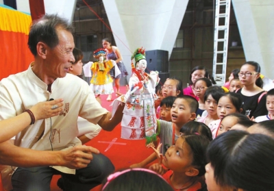 南安市掌中木偶傳承人黃通行指導(dǎo)小學(xué)生操演木偶。　