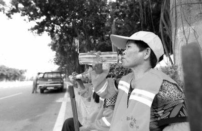 酷暑難耐，清潔工在小憩時為自己補充水分。本報記者