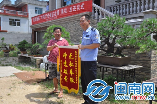 黃先生為民警送來錦旗，背后是黑松盆栽