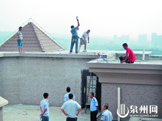 執(zhí)法人員組織工人對高層樓頂?shù)倪`法建筑進(jìn)行拆除